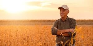 Médio produtor brasileiro ao lado de maquinário agrícola